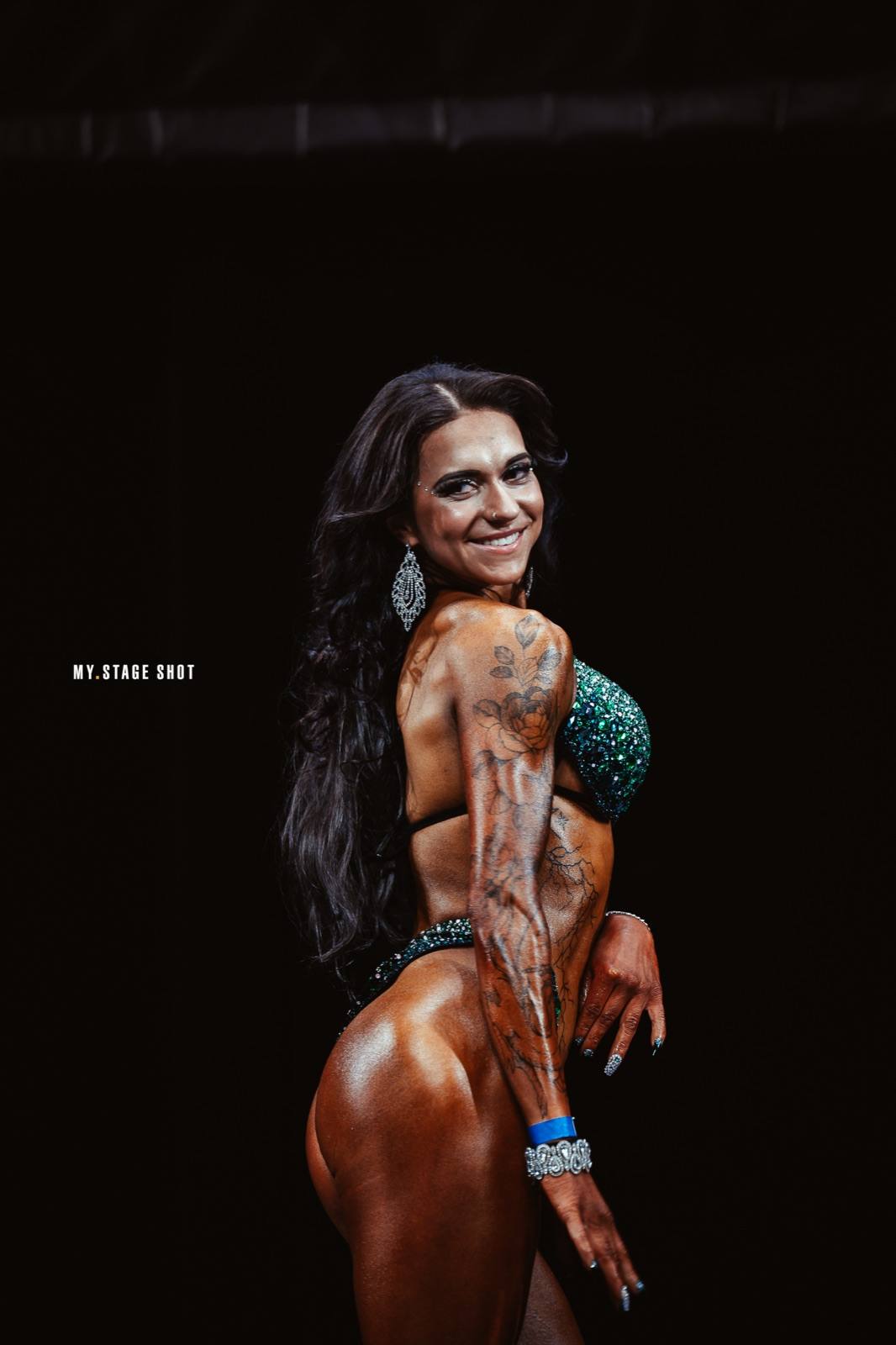Bikini-Athletin mit tätowiertem Arm in der Seitpose
