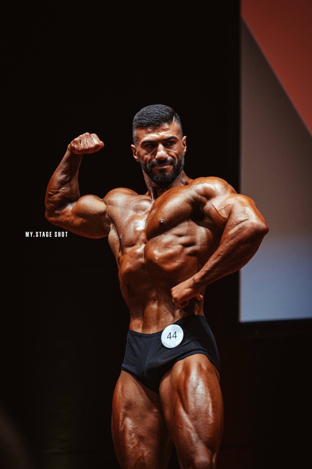 Bodybuilder in der Front-Doppelbizeps-Pose auf der Bühne