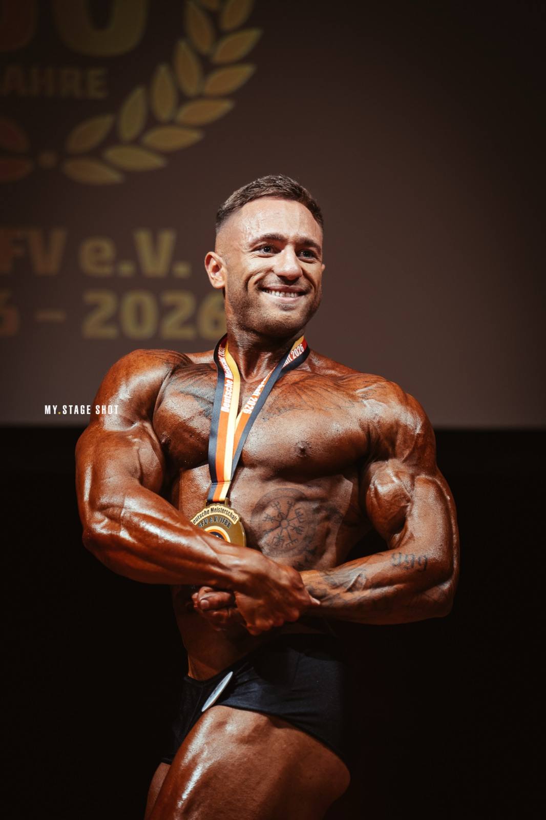 Bodybuilder mit Goldmedaille in der Most-Muscular-Pose